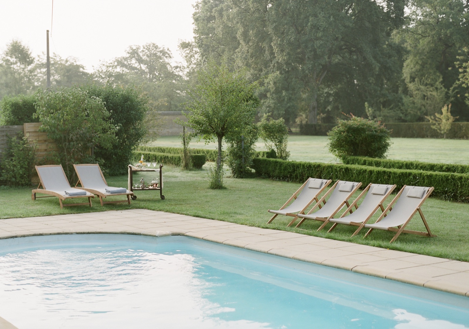 Deck chairs and loungers on the grass beside the pool